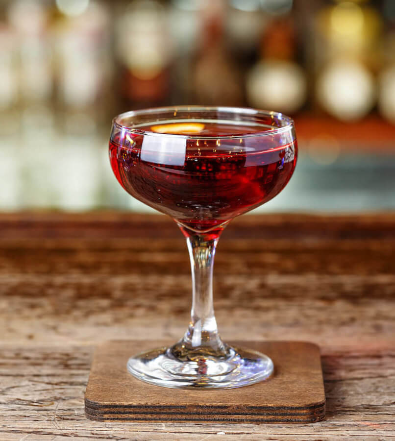 Mahattan Cocktail roter Manhattan Cocktail in einer Cocktailschale auf Holztisch