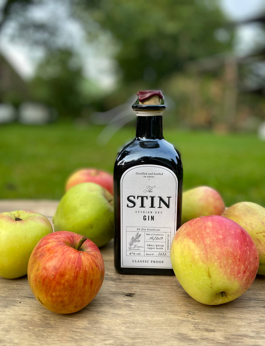 Flasche Stin Gin mit rotgelben Äpfeln im Garten