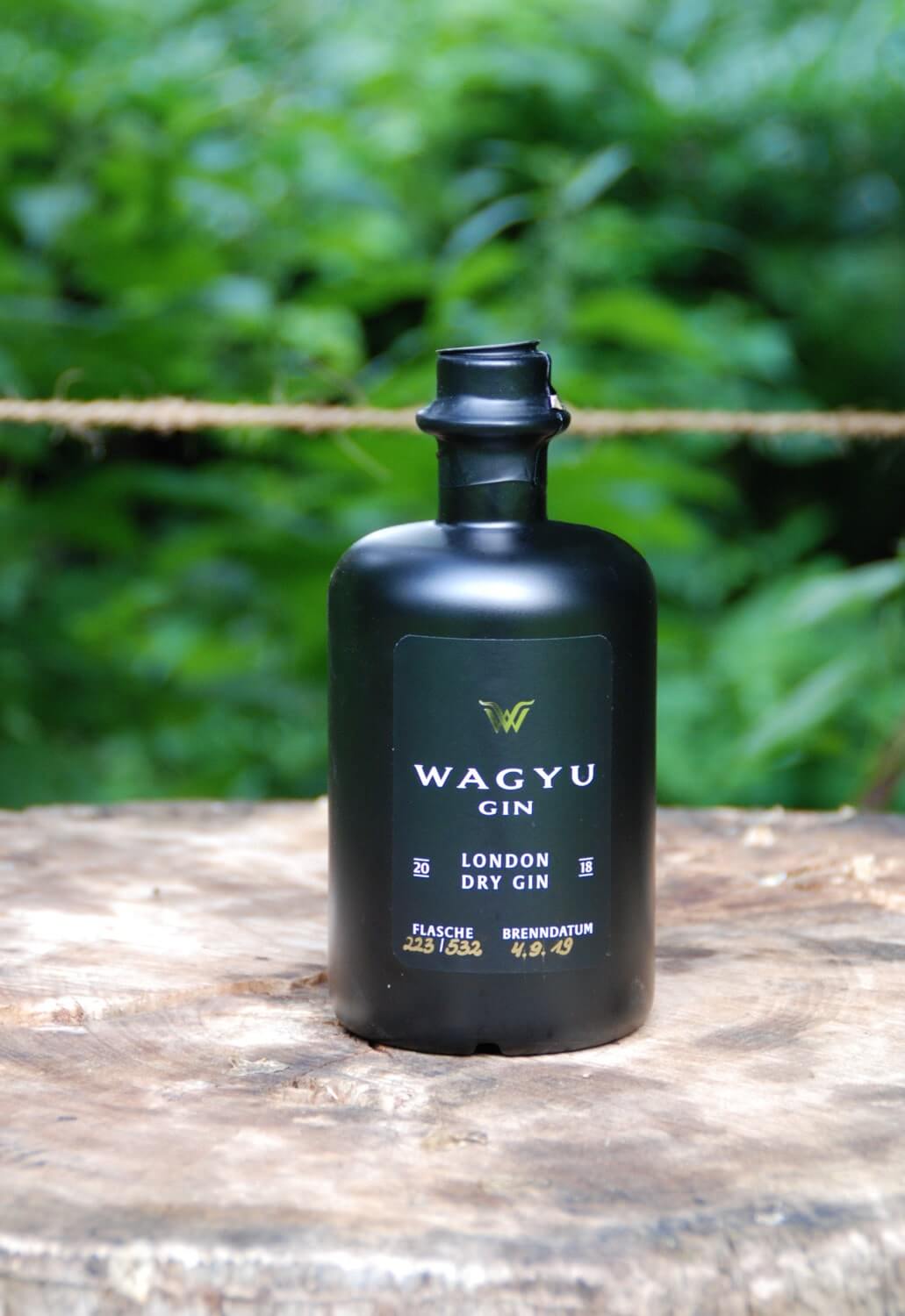 Wagyu London Dry Gin auf einem Holzklotz im Garten
