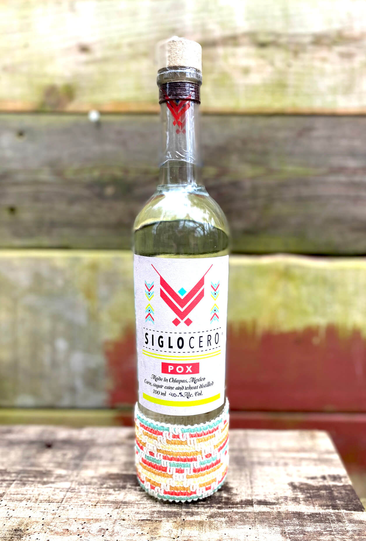 Flasche Siglo Cero Pox vor buntem Holz